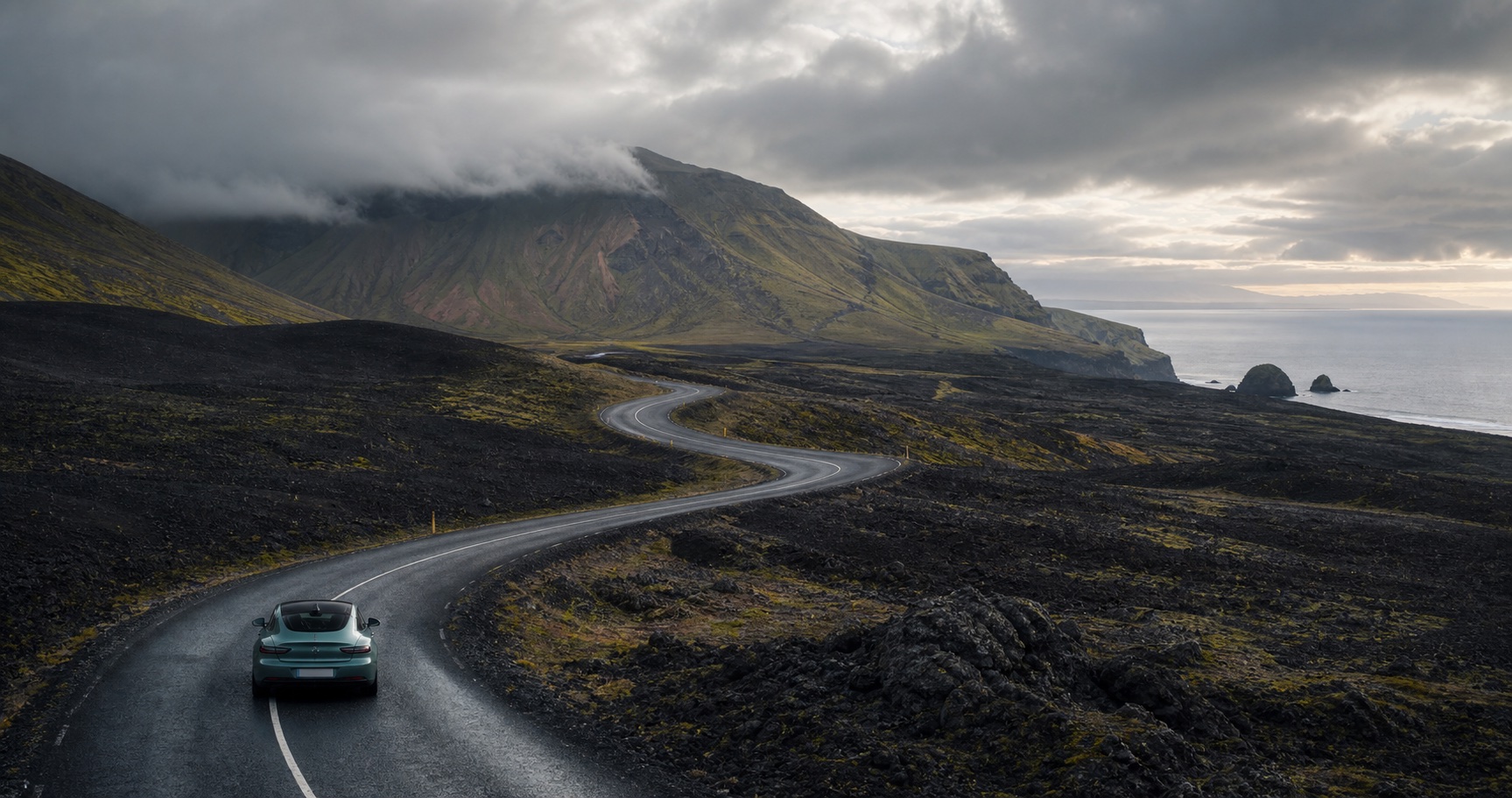A modern car on an open volcanic island road with wide views.
